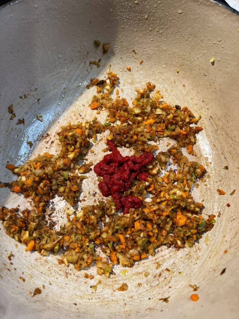 Sautéed vegetables with tomato paste in a deep pot.