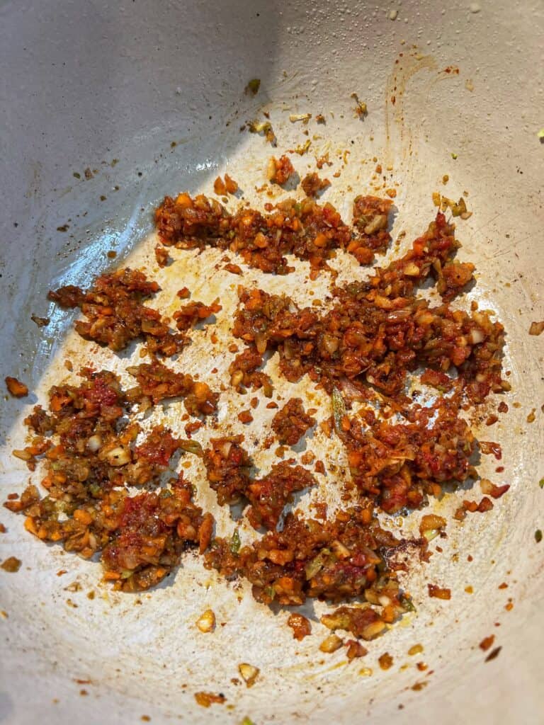 Vegetables and tomato paste sautéed in a deep pot.