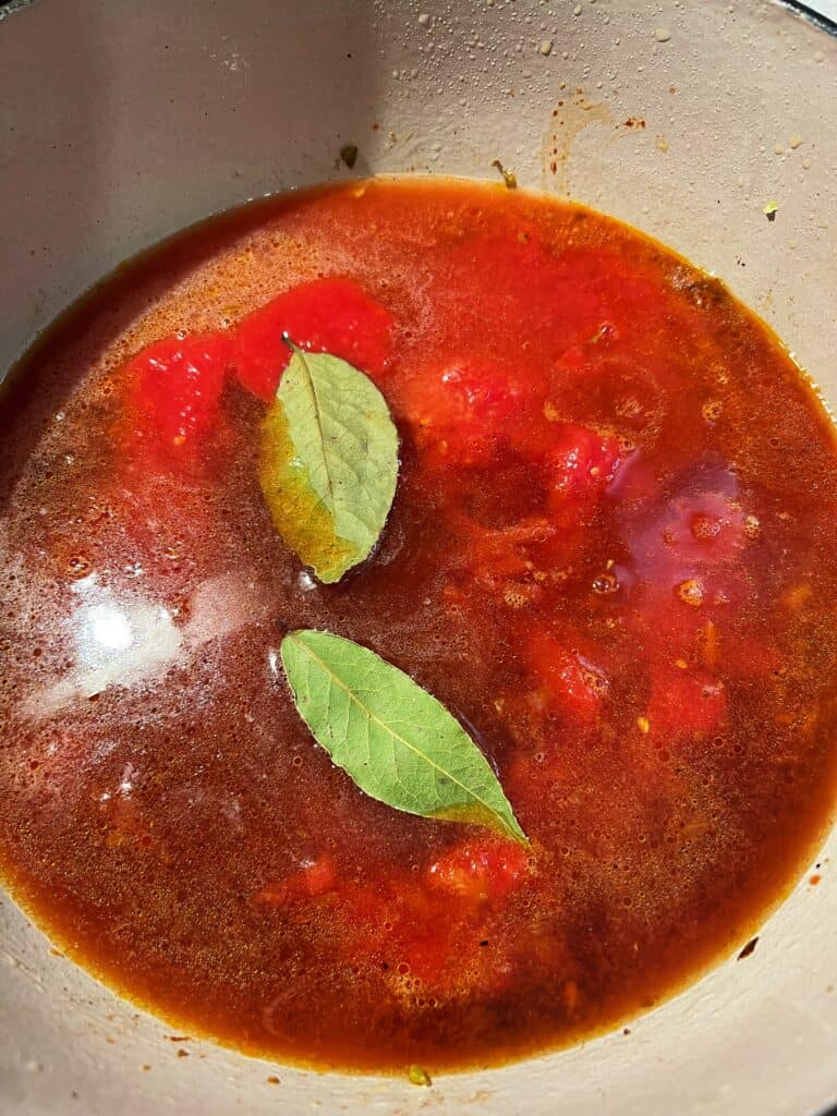 Stock, crushed tomatoes and two bay leaves in a deep pot.