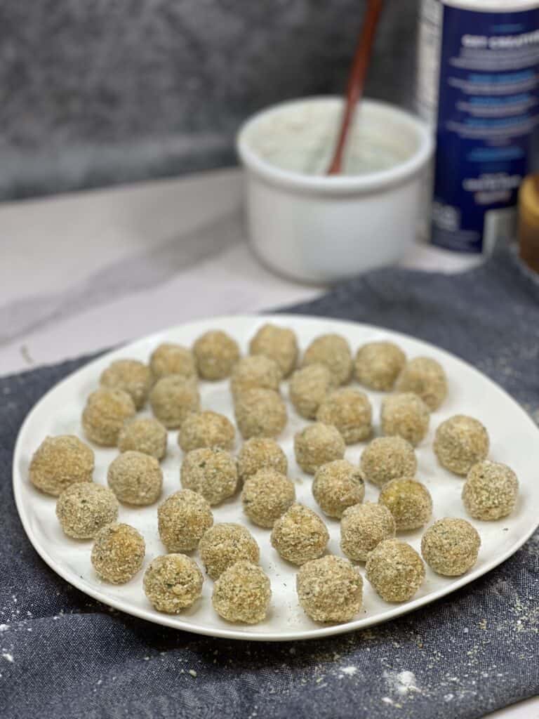 A white platter filled with breaded olives.