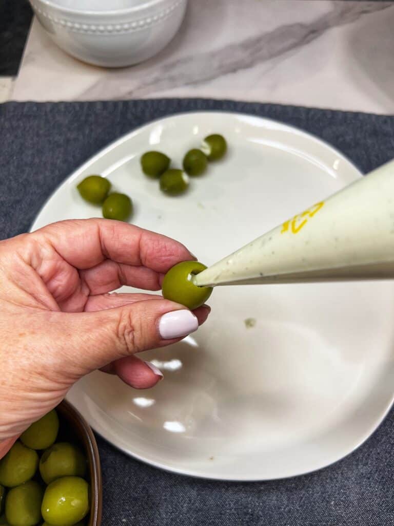 Piping a ricotta/blue cheese mixture into a green olive.