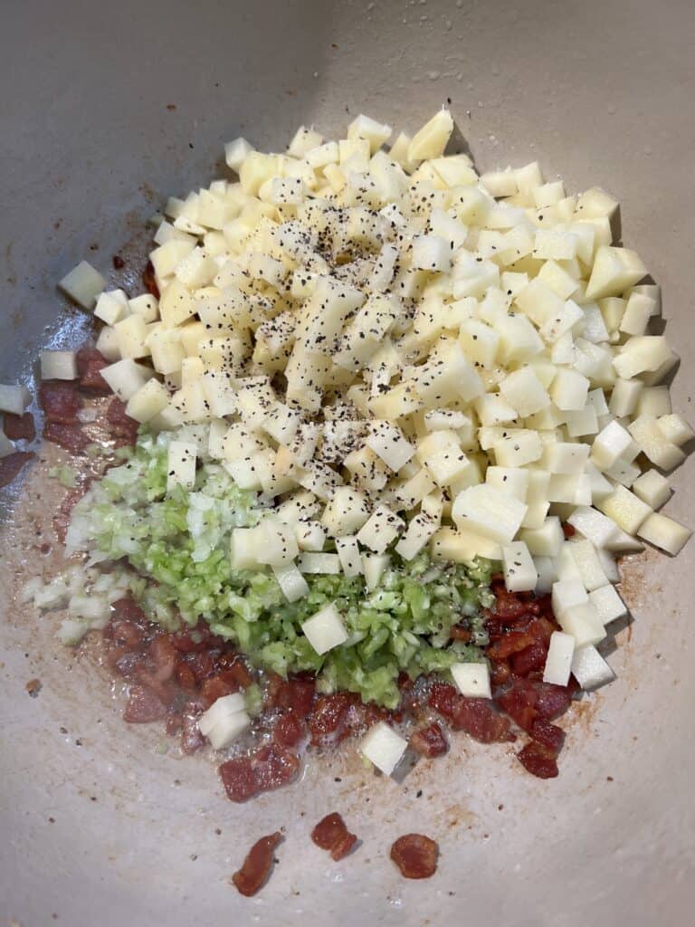 Diced potatoes, minced celery and onions added to a pot with crisp, diced bacon.