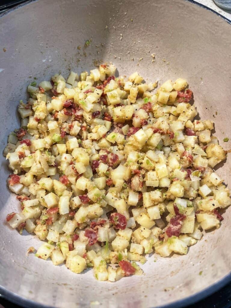 Diced potatoes and crisp, diced bacon sprinkled with flour in a soup pot.