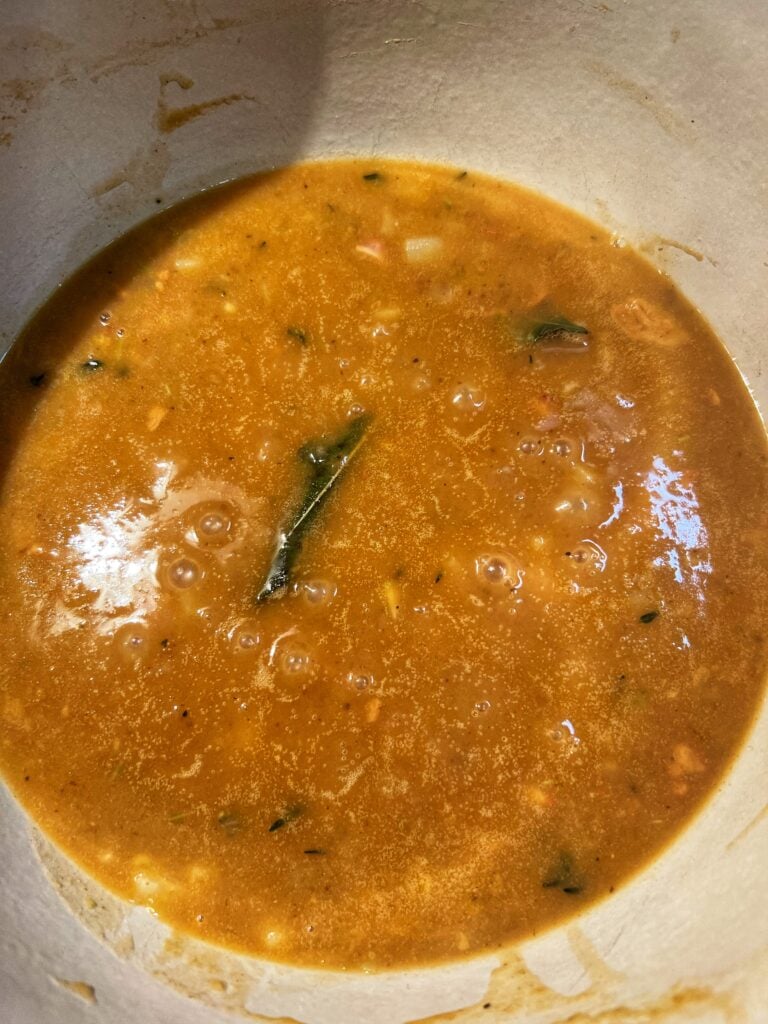 Simmered vegetables and shrimp stock in a pot.