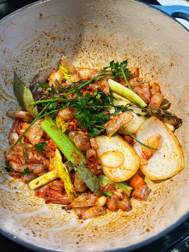 Sautéed vegetables and shrimp shells in a pot.