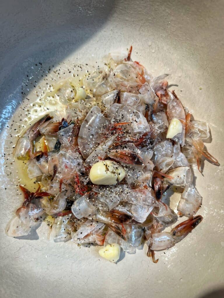 Sautéing shrimp shells and smashed garlic in a stock pot for shrimp stock.