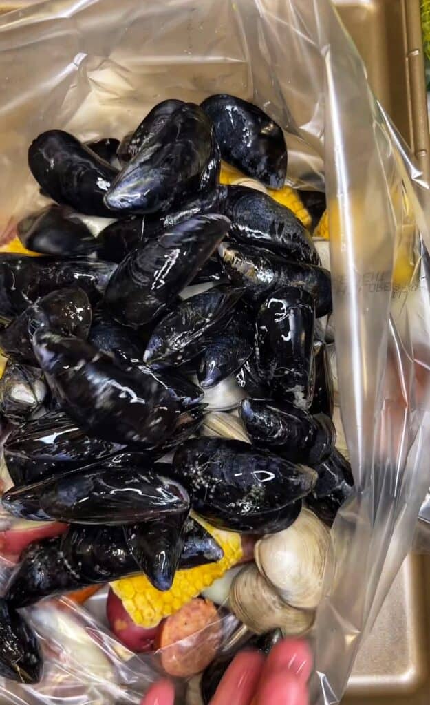 Clams and mussels added to an oven bag for a seafood boil.