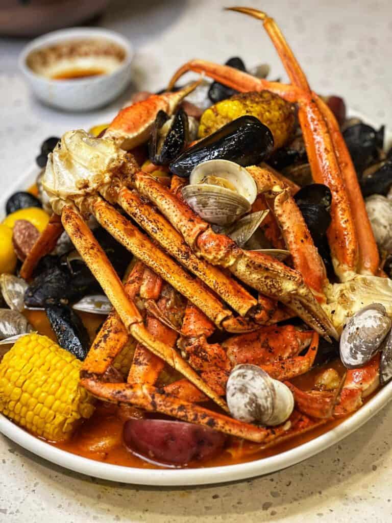 A platter of a seafood boil with steamed seafood; mussels, crab legs, clams, potatoes and corn.