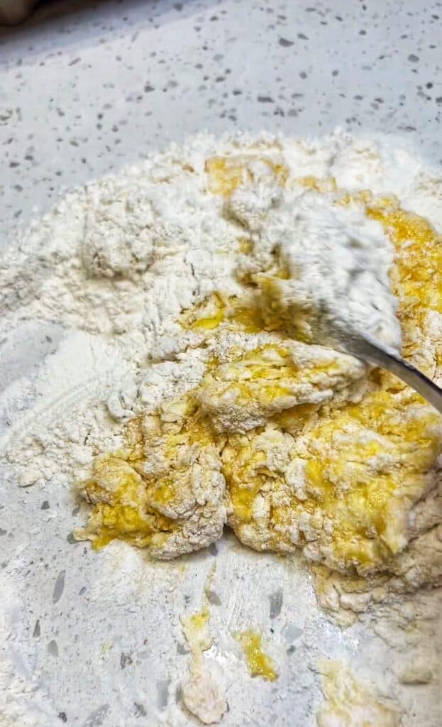Finishing incorporating flour into eggs for pasta dough.