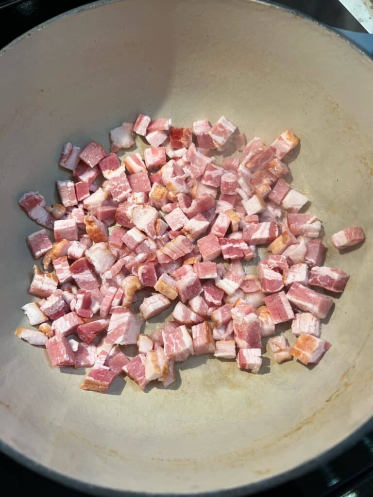 Diced bacon frying in a dutch oven.