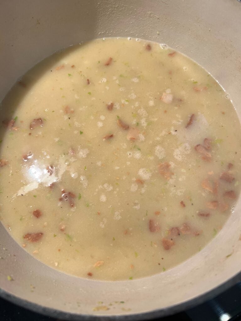 Lobster stock added to the pot with floured vegetables and diced bacon.