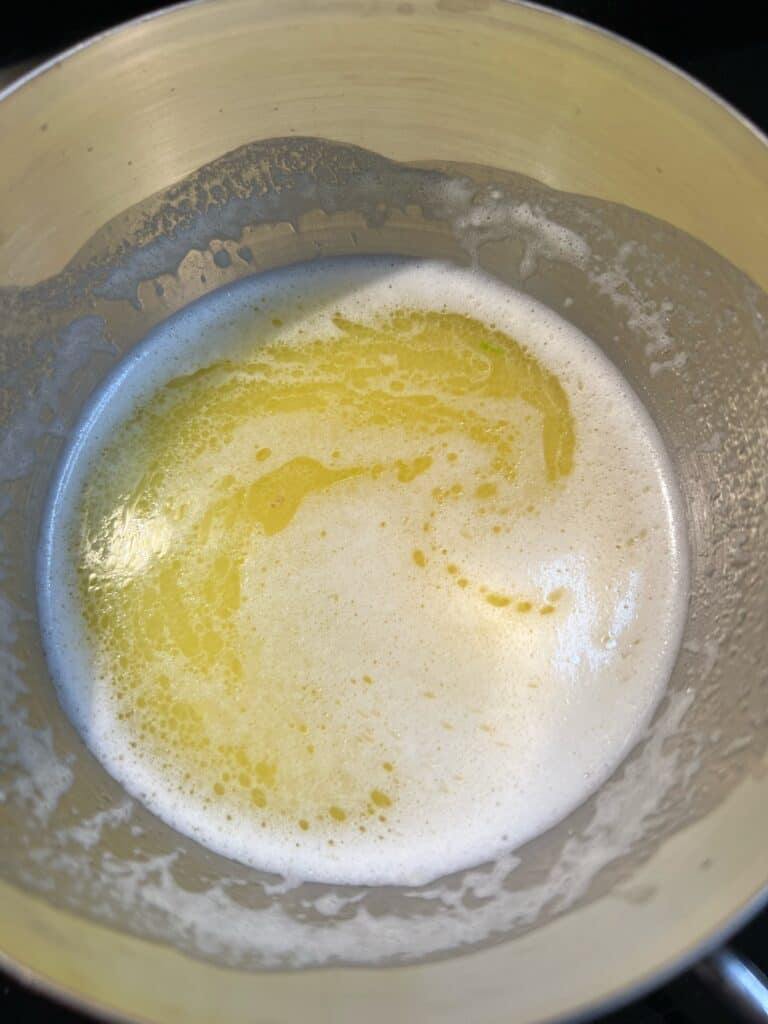 Melted butter, minced garlic, white wine and lemon juice in a small stainless steel pot.