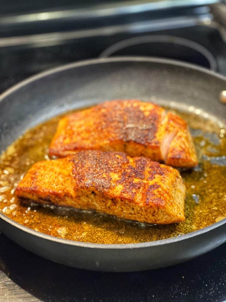 Two seared salmon filets in a non-stick pan.