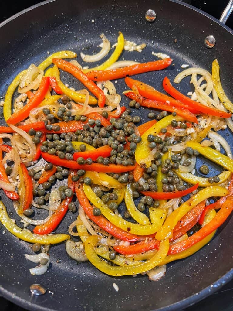 Capers sautéing with sliced onions, bell peppers and minced garlic in a non-stick pan.