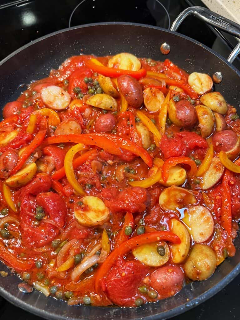 A tomato-based sauced with vegetables simmering in a non-stick pan.