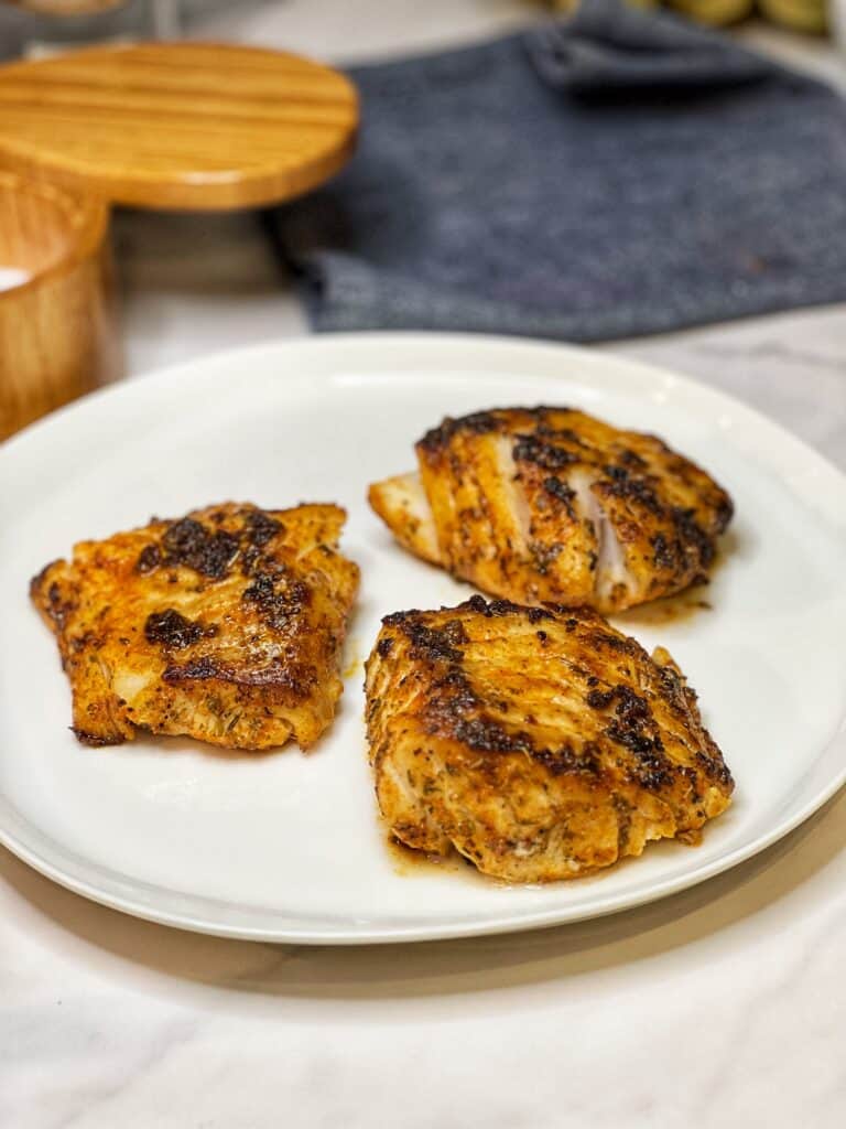 Three blackened cod filets sitting on a white platter.
