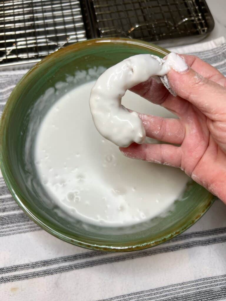 Me holding a piece of tail-on shrimp that has been coated in flour and dipped into coconut cream.