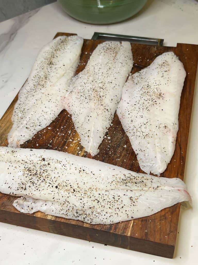 Four orange roughy filets seasoned with salt and pepper.