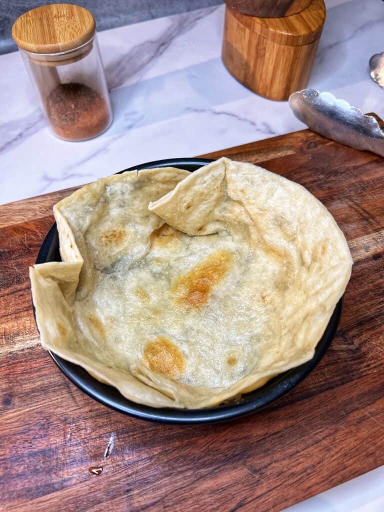A semi-fried, flour tortilla formed to fit into a small round baking pan to create a taco bowl shell.