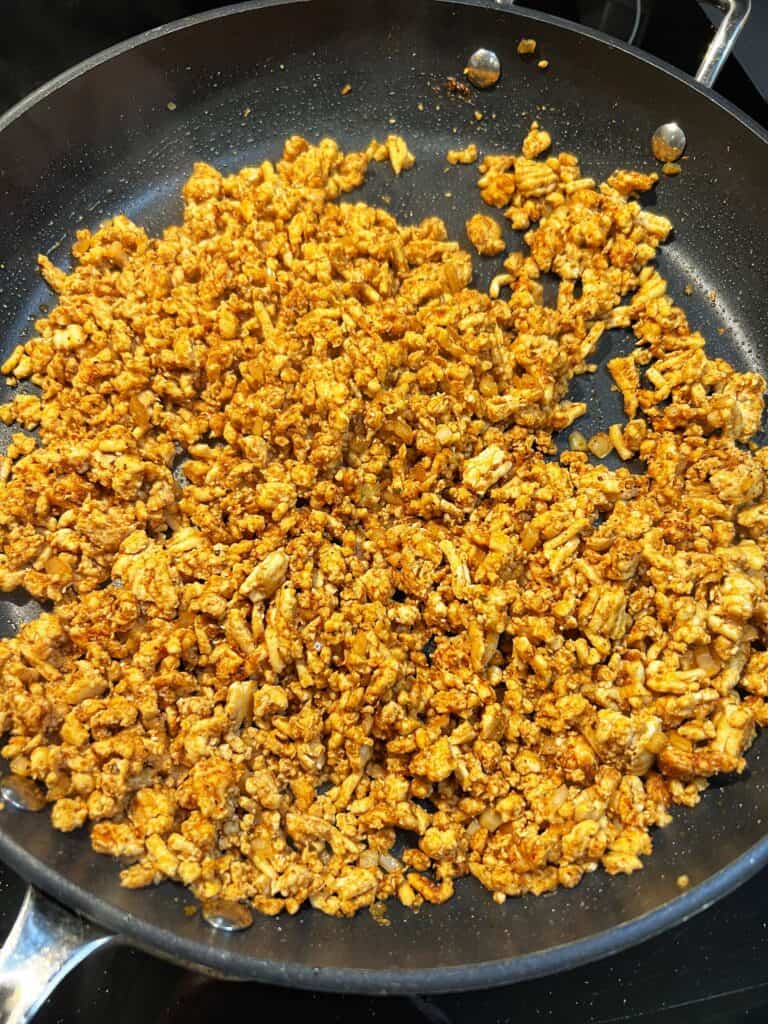 Cooked ground chicken seasoned with taco seasoning in a non-stick pan.