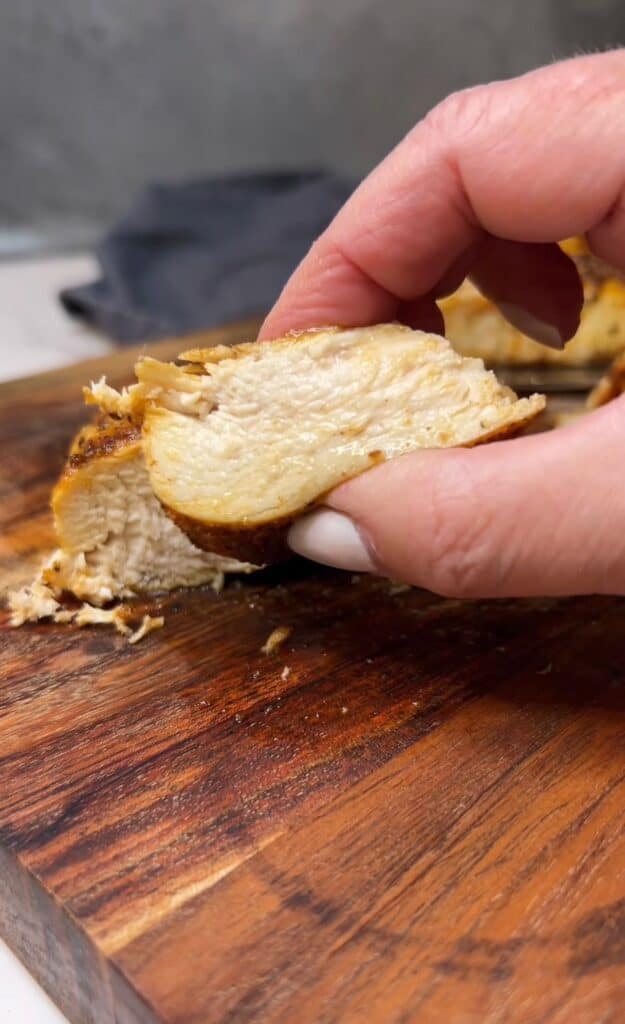 Me holding a slice of juicy chicken breast to show how juicy it is inside.