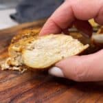 Me holding a piece of juicy, sliced chicken breasts between my two fingers to show how juicy the chicken is.