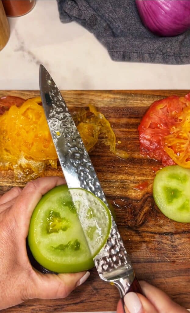Thinly slicing a green heirloom tomato for heirloom tomato carpaccio salad.