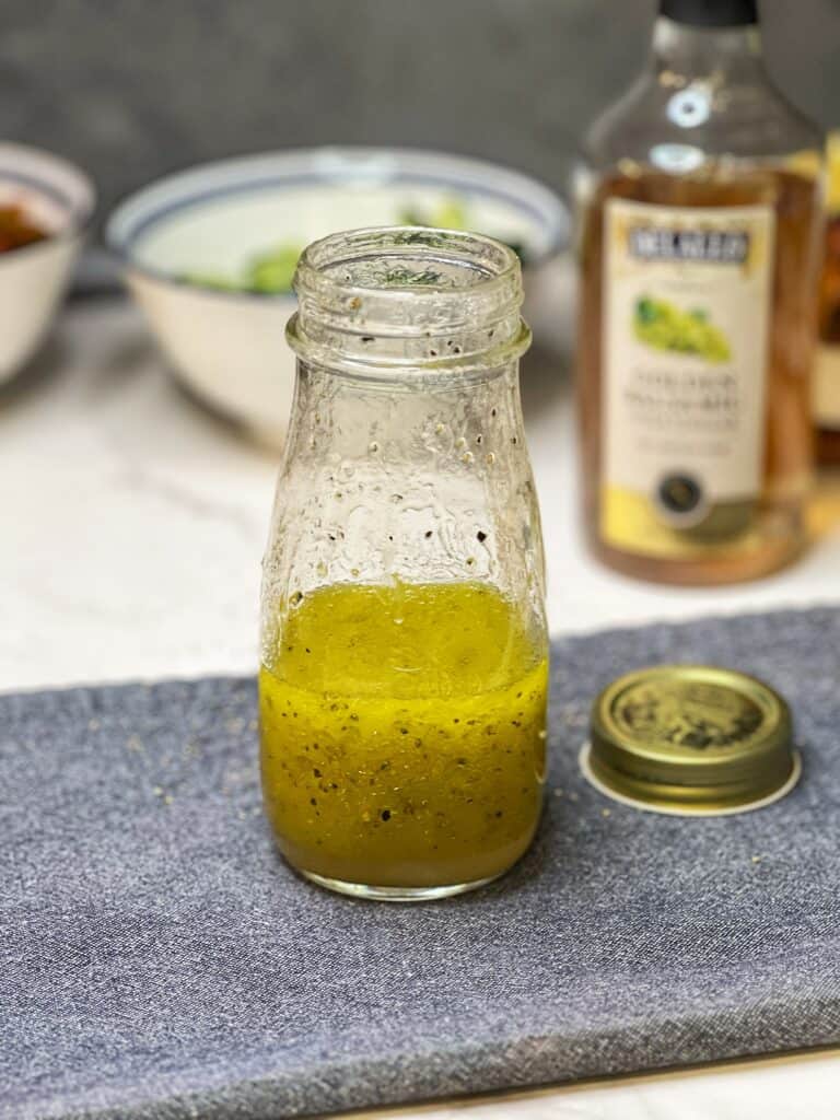 A dressing of olive oil and vinegar in a jar for healthy grilled shrimp salad.