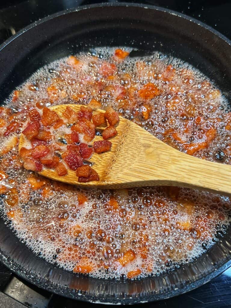 A small non-stick pan of crisp diced bacon.