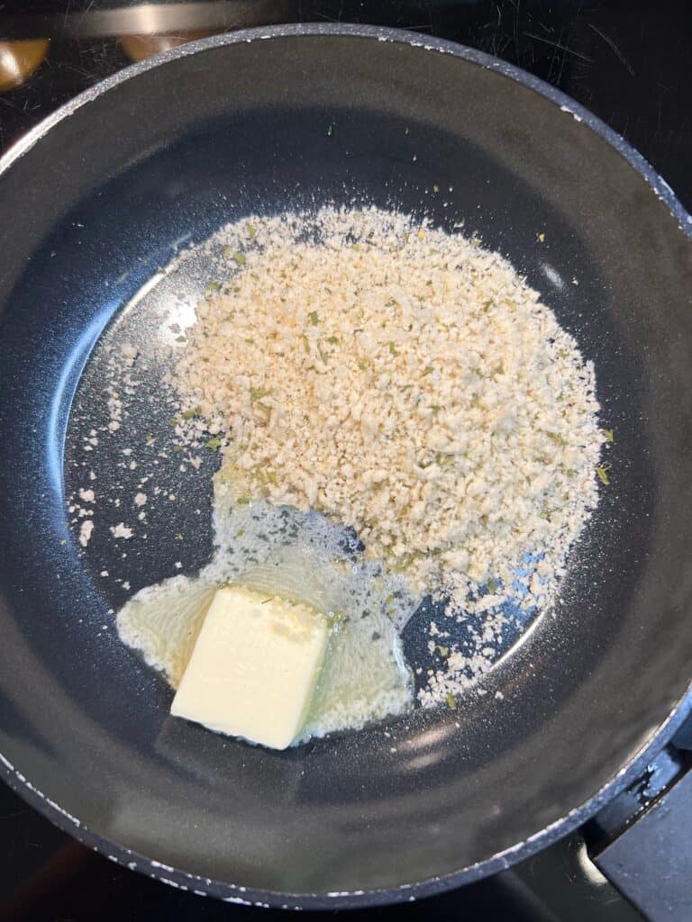 A small non-stick pan of butter melting with panko breadcrumbs.