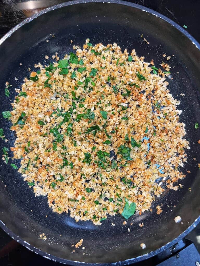 Toasted panko with fresh parsley in a non-stick pan for Rockefeller Style Grilled Oysters.