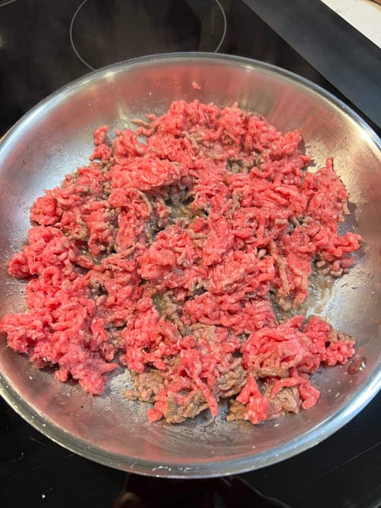 Browning ground beef in a stainless steel pan.