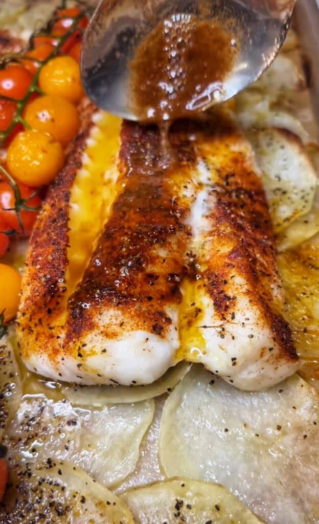 Spooning brown butter over a piece of baked cod.