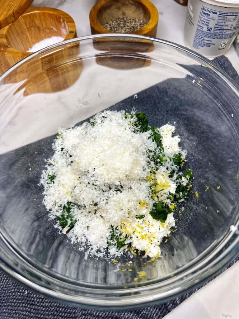 Cream cheese, spinach, Parmesan cheese and lemon zest in a glass bowl.