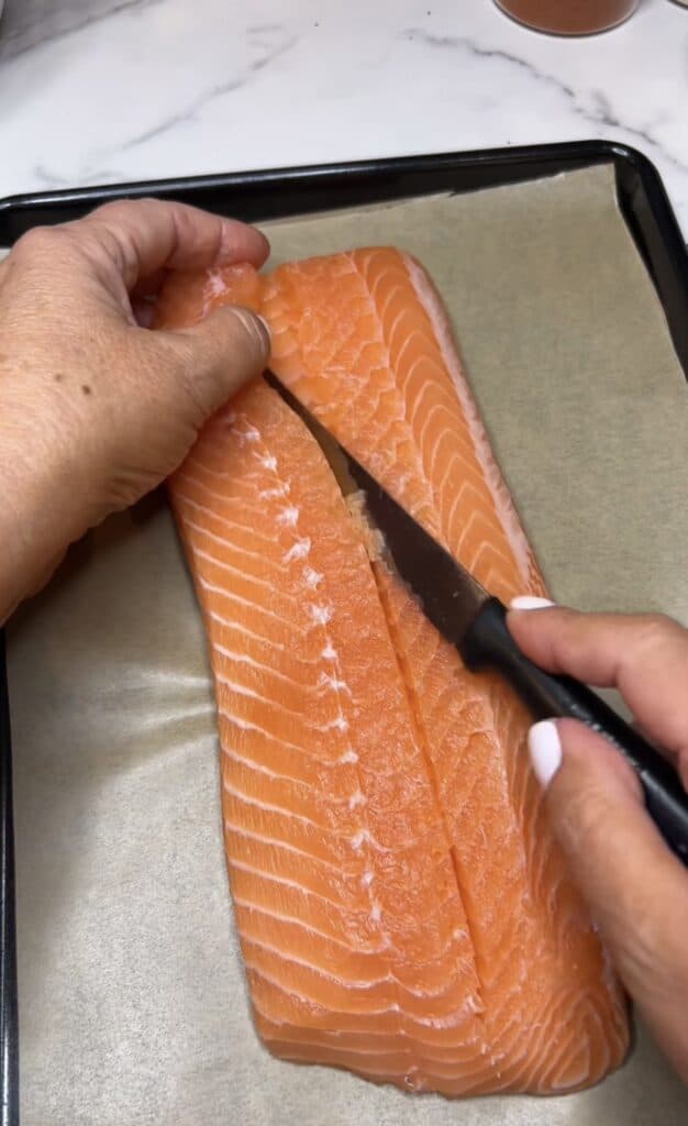 Use a knife to cut a flap and open up one side of a salmon filet.