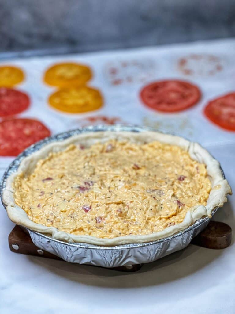 A layer of pimento cheese in a round pie tin.
