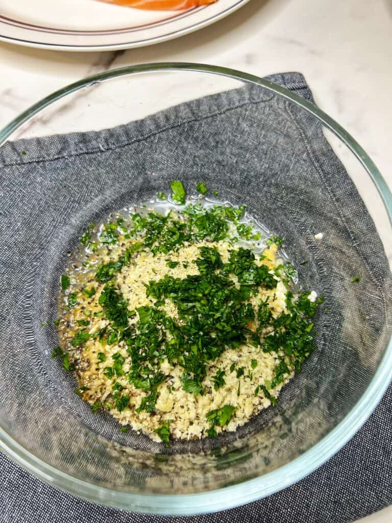 Mayo, breadcrumbs, seasoning, mustard and fresh parsley in a small glass bowl.
