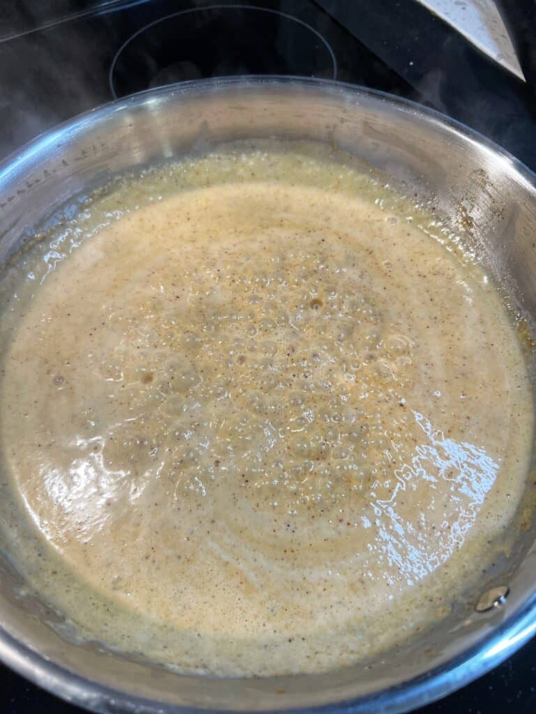 A creamy Cajun sauce simmering in a stainless steel pan.