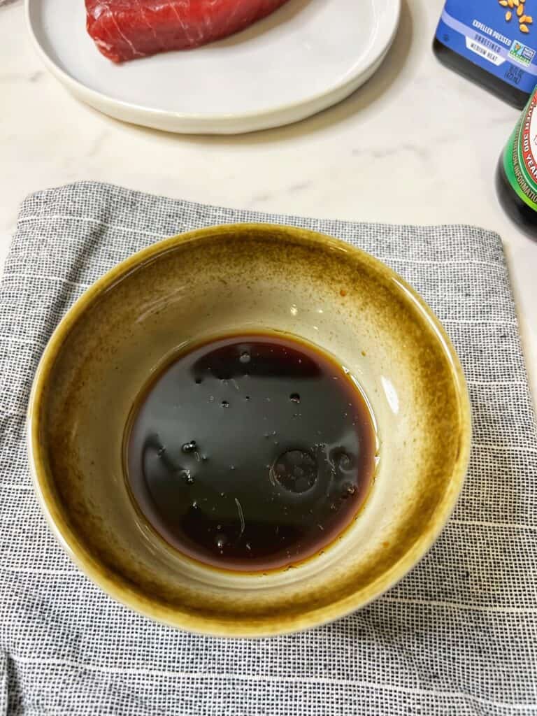 A small brown bowl filled with a sauce made from Ponzu sauce, soy and sesame oil.