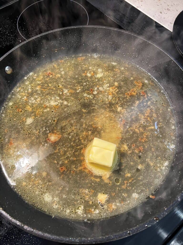 Chicken stock with butter cooking in a non-stick pan for piccata sauce.