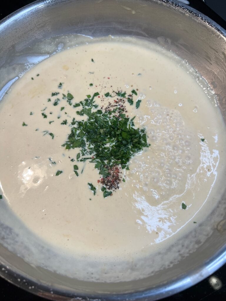Fresh chopped parsley and cracked black pepper added to a pan of Dijon cream sauce.