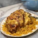 A platter of roast pork with sauerkraut laying around the edges of the roast.