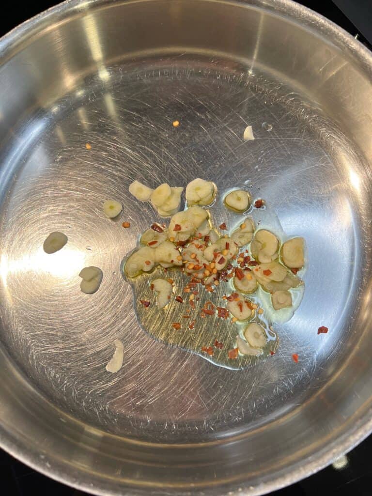 Thinly sliced garlic and crushed red pepper flakes in a deep sauté pan with olive oil.