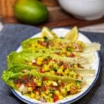 A white platter holding Romaine lettuce cups filled with Blackened Cod with Mango Salsa.