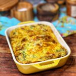 A cottage cheese baked eggs casserole in a yellow, rectangular baking dish. The top of the dish is browned from the cheese.