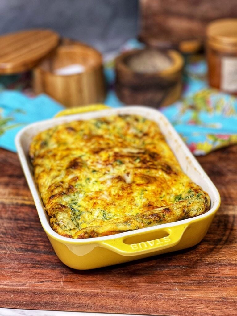 A cottage cheese baked eggs casserole in a yellow, rectangular baking dish. The top of the dish is browned from the cheese.