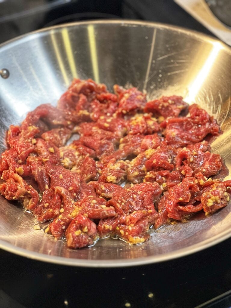 Searing marinated flank steak in a wok.