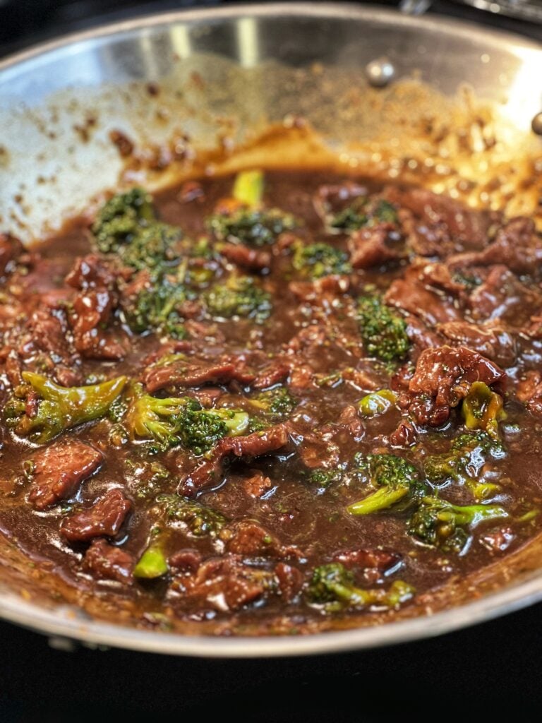 A wok full of beef and broccoli in a brown sauce.