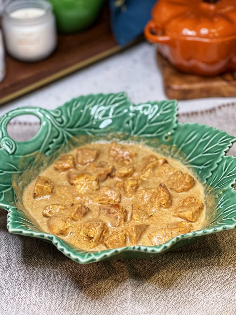 Cubed bread soaking in a in a pumpkin custard in a green leaf bowl.