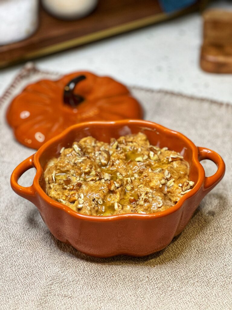 Pumpkin bread pudding in an orange pumpkin-shaped dish ready to be baked.